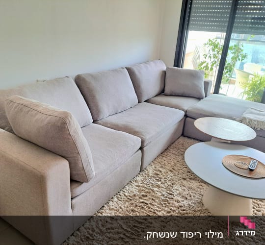 ספה אפורה עם שולחנות עגולים בסלון מואר